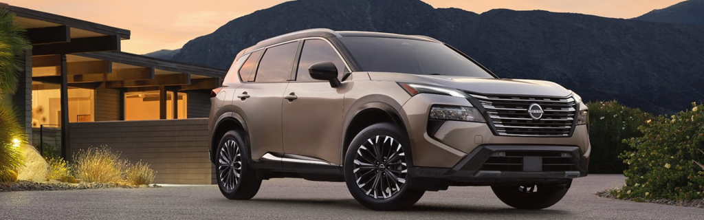 Champagne Nissan Rogue parked in front of a modern home at sunset.